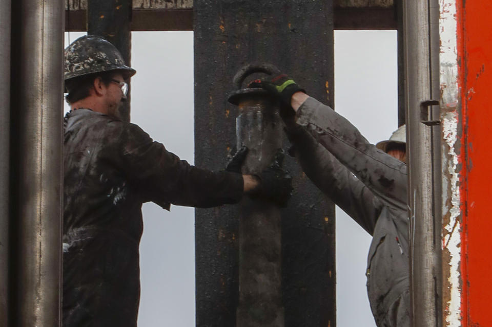 In this photo made on Thursday, March 12, 2020, men work to change equipment on the well drilling rig at a Seneca Resources shale gas well drilling site in St. Mary's, Pa. (AP Photo/Keith Srakocic)