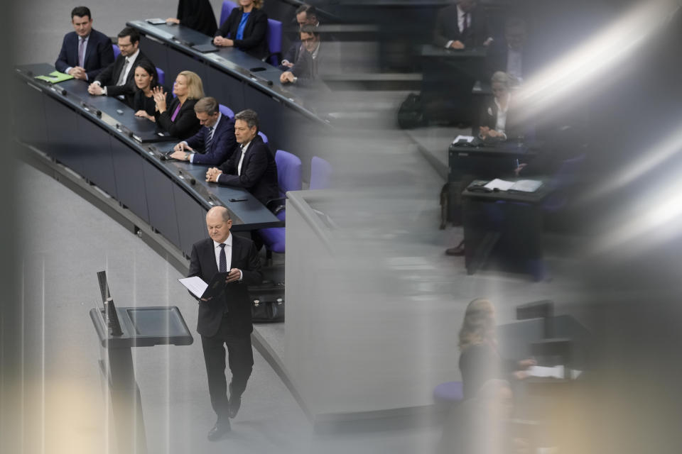 German Chancellor Olaf Scholz, center, walks to the podium for a speech about Germany's budget crisis at the parliament Bundestag in Berlin, Germany, Tuesday, Nov. 28, 2023. With its economy already struggling, Germany now is wrestling to find a way out of a budget crisis after a court struck down billions in funding for clean energy projects and help for people facing high energy bills because of Russia's war in Ukraine. (AP Photo/Markus Schreiber)