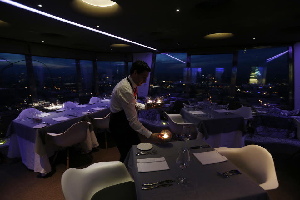 In this picture taken March 6, 2013, a waiter sets a candle on a table in a restaurant at the Zizkov television tower in Prague, Czech Republic. Following its completion in 1992, the 216-meter (236-yard) tall television tower in the Czech capital has become a dominant landmark of the city skyline that offers a breathtaking view of Prague from its restaurant and observation desk. (AP Photo/Petr David Josek)