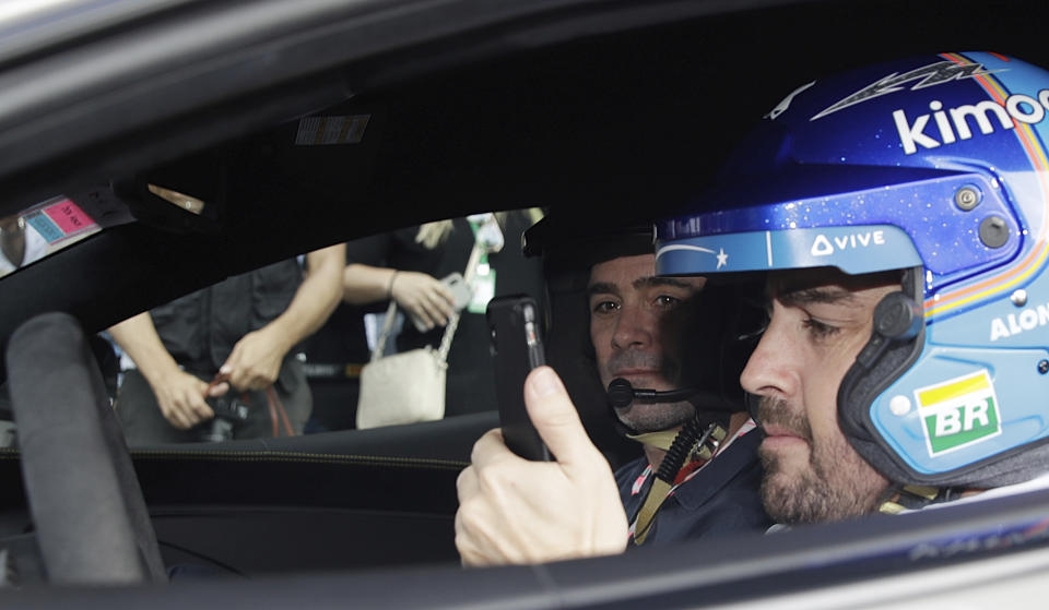 Mclaren driver Fernando Alonso of Spain, right, is flanked by Nascar World champion Jimmie Johnson before driving a McLaren 570S car at the Yas Marina racetrack in Abu Dhabi, United Arab Emirates, Saturday, Nov. 24, 2018. Seven-time NASCAR champion Jimmie Johnson and two-time Formula One champion Fernando Alonso drive Pirelli hot laps together around the Abu Dhabi F1 track on Saturday afternoon. (AP Photo/Luca Bruno)