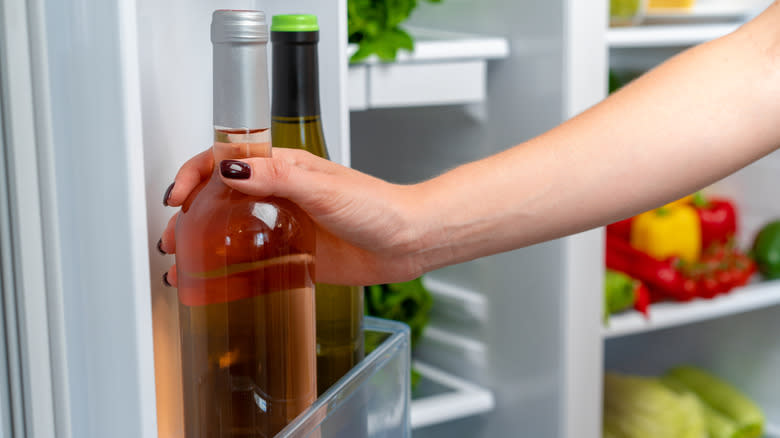 person taking wine bottle from fridge