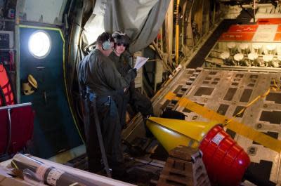 Petty Officer Third Class Jeremy Ballard and Aviation Electronics Technician Third Class James Link of the US Coast Guard prepare to deploy a buoy.