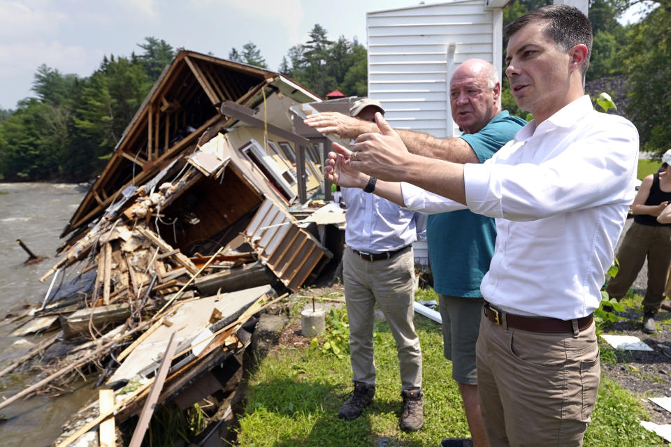 Transportation Secretary Pete Buttigieg, right, listens to Perry Hollyer, owner of the Inn by the River, describe flood waters, which destroyed his family's hotel, along the banks of the Lamoille River, Monday, July 17, 2023, in Hardwick, Vt. Last week's storms dumped up to two months' worth of rain in a couple of days in parts of Vermont and New York. (AP Photo/Charles Krupa)