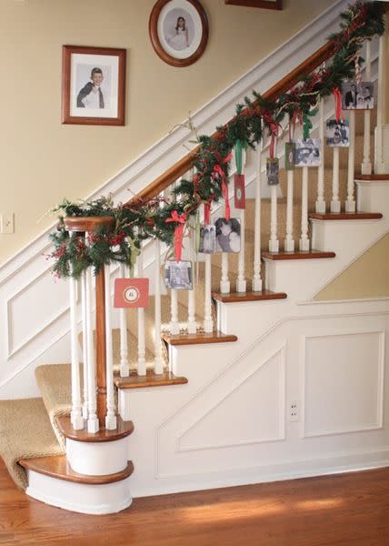 <p>Display family photos and Christmas cards by hanging them on your banister's garland. </p><p>See more at <a href="http://www.memoriesoncloverlane.com/2010/11/photo-garland.html" rel="nofollow noopener" target="_blank" data-ylk="slk:Clover Lane;elm:context_link;itc:0;sec:content-canvas" class="link ">Clover Lane</a>. </p>