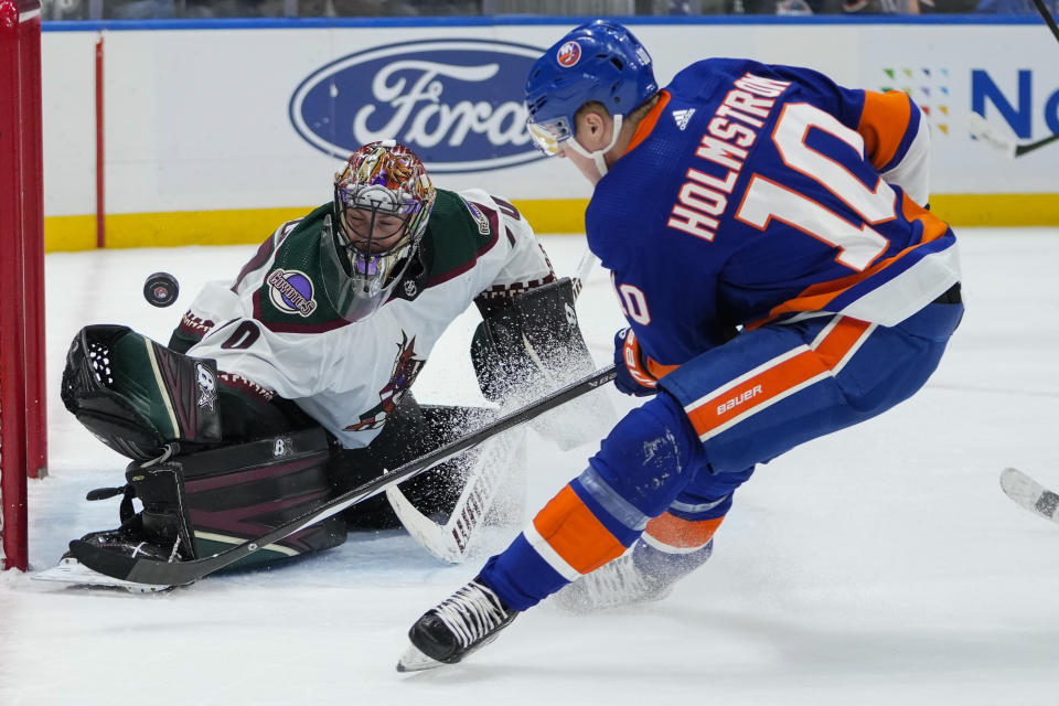 Arizona Coyotes goaltender Karel Vejmelka, left, stops a shot on goal by New York Islanders' Simon Holmstrom (10) during the second period of an NHL hockey game Tuesday, Oct. 17, 2023, in Elmont, N.Y. (AP Photo/Frank Franklin II)