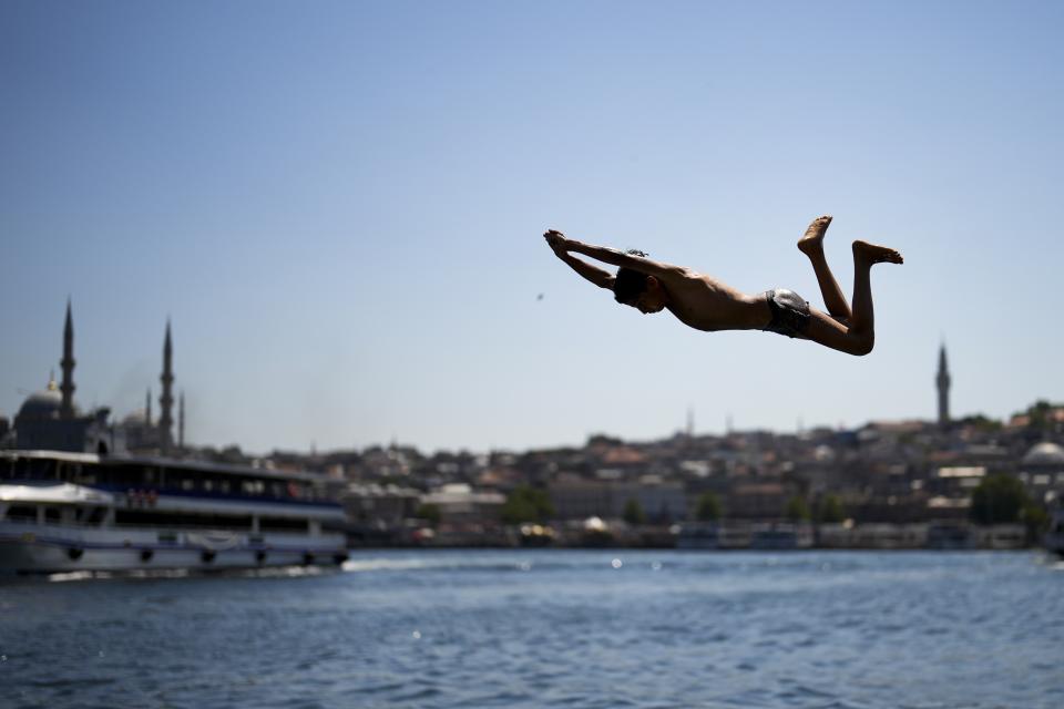A youngster dives into the Bosphorus next to the Golden Horn during a hot summer day in Istanbul, Turkey, Wednesday, July 19, 2023. (AP Photo/Francisco Seco)