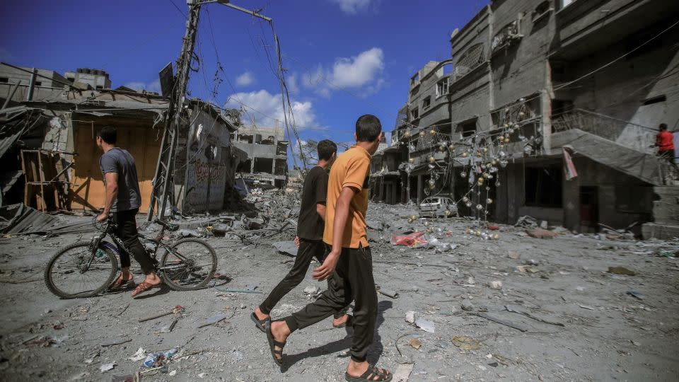 People walk amid the destruction of houses and streets in Khan Younis, located in the southern Gaza Strip. - Mohamed Zaanoun/Middle East Images/AFP/Getty Images