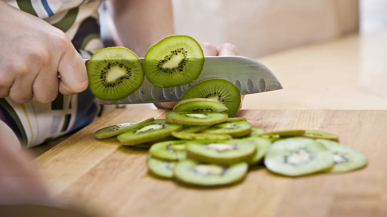 Hands slicing a kiwi