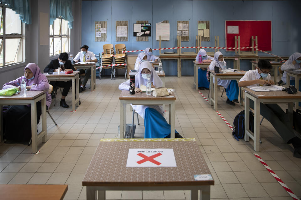 Students wearing face masks and maintaining social distancing at a classroom during the first day of school reopening at a high school in Putrajaya, Malaysia, Wednesday, June 24, 2020. Malaysia began reopening schools Wednesday while entering the Recovery Movement Control Order (RMCO) after three months of coronavirus restrictions. (AP Photo/Vincent Thian)