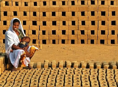 An Indian brick kiln worker feed her child at a brick factory in Gadopur village 30 km (19 miles) from Allahabad, February 18, 2006. REUTERS/Jitendra Prakash/Files