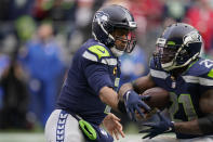 Seattle Seahawks quarterback Russell Wilson, left, hands off to running back Adrian Peterson, right, during the first half of an NFL football game against the San Francisco 49ers, Sunday, Dec. 5, 2021, in Seattle. (AP Photo/Elaine Thompson)