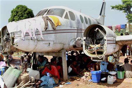 People displaced by fighting between rival militias take shelter under an old broken airplane at the airport in Bangui