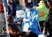 A medical student from Touro University Nevada talks with a man in a temporary parking lot with spaces marked for social distancing in Las Vegas