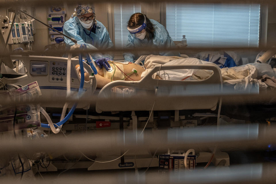 FILE - In this Dec. 22, 2020 file photo Phlebotomist lab assistant Jennifer Cukati, right, and Registered Nurse Carina Klescewski, left, care for a COVID-19 patient inside the Sutter Roseville Medical Center ICU in Roseville, Calif. California became the first state to record 2 million confirmed coronavirus cases, reaching the milestone on Christmas Eve as close to the entire state was under a strict stay-at-home order and hospitals were flooded with the largest crush of cases since the pandemic began. (Renee C. Byer/The Sacramento Bee via AP, Pool,File)