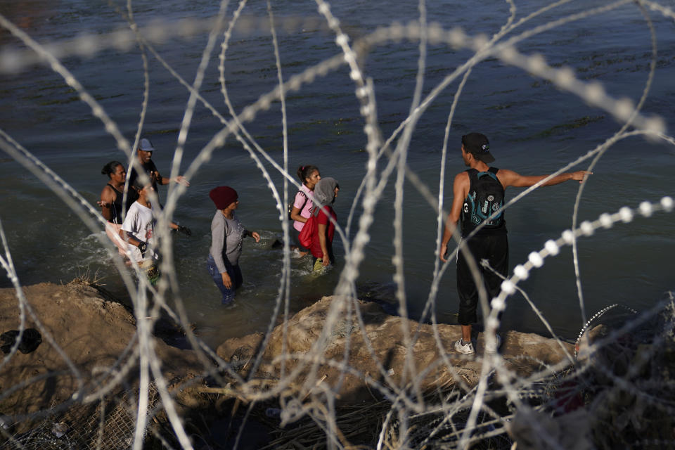 Migrants walk in the Rio Grande along a wall of concertina wire as they try to cross into the U.S. from Mexico, Friday, Sept. 22, 2023, in Eagle Pass, Texas. (AP Photo/Eric Gay)