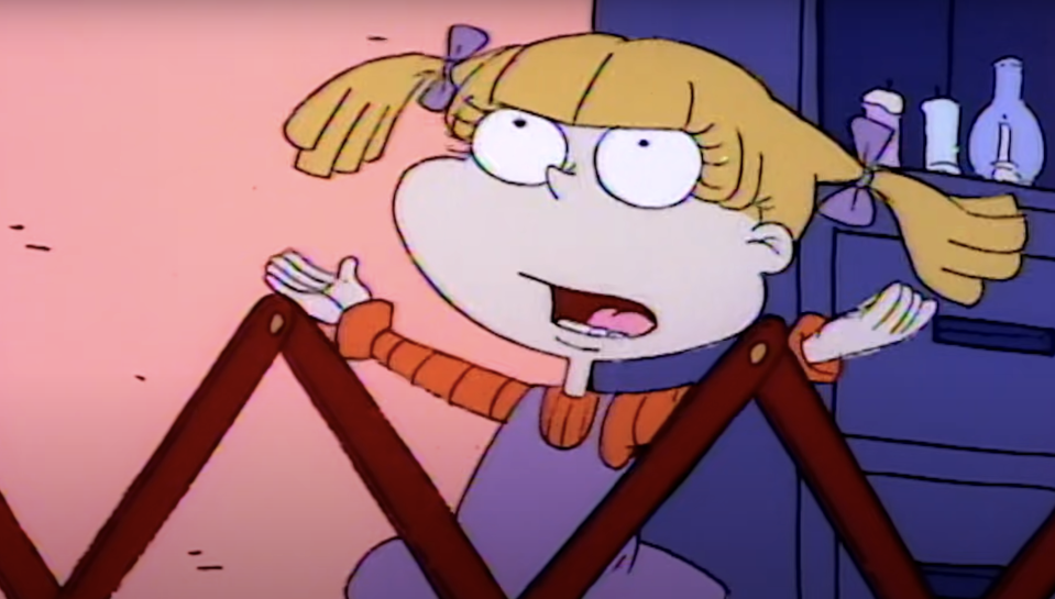 Character Angelica from the animated series 'Rugrats', looking frustrated while standing in a playpen