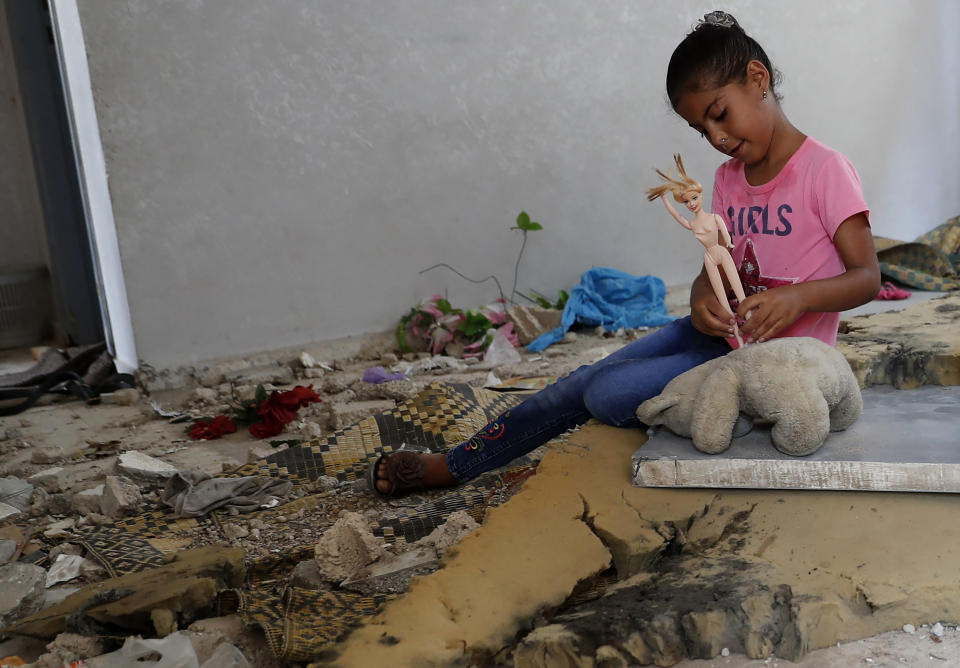 Rahaf Abu Fares, 10, who lost four family members when an Israeli artillery bombardment hit his family house during the 11-day war between Israel and Gaza's Hamas rulers in May, plays with a toy amid the rubble of his house, at the Bedouin village of Umm Al-Nasr, outside the town of Beit Lahia, northern Gaza Strip, Wednesday, Aug. 4, 2021. After initially finding no grounds for disciplinary action, the Israeli military says it is investigating the artillery bombardment that killed six Palestinians, including an infant, in the Gaza Strip last May. (AP Photo/Adel Hana)