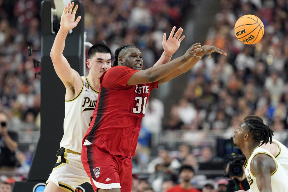 NC State forward DJ Burns Jr. (30) dishes off as Purdue center Zach Edey defends during the second half of the NCAA college basketball game at the Final Four, Saturday, April 6, 2024, in Glendale, Ariz. (AP Photo/Brynn Anderson )