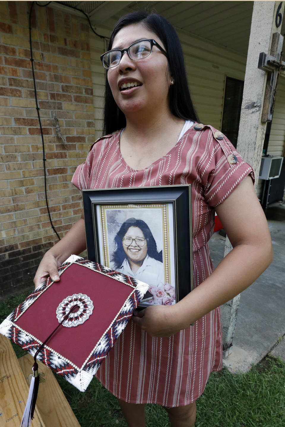Kristina Taylor, 18, holds a portrait of her late mother, Sharon Taylor, and the special beaded mortar board she would have worn during graduation ceremonies at Choctaw Central High School, Tuesday, July 22, 2020 in Tucker, Miss. For the Taylor family, June 2020 was supposed to be for celebrating daughter Kristina being selected as valedictorian at Choctaw Central High, the tribal high school for the Mississippi Band of Choctaw Indians. Instead, the family buried the mother, a victim of COVID-19. (AP Photo/Rogelio V. Solis)