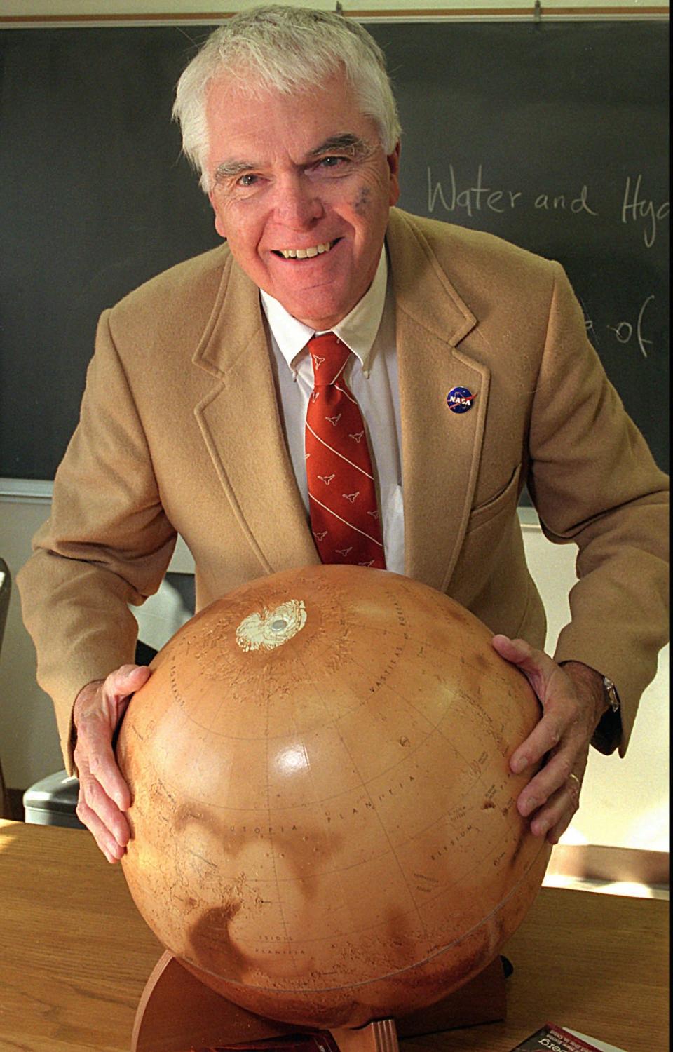 Hans Mark holds a replica of Mars in 1996.