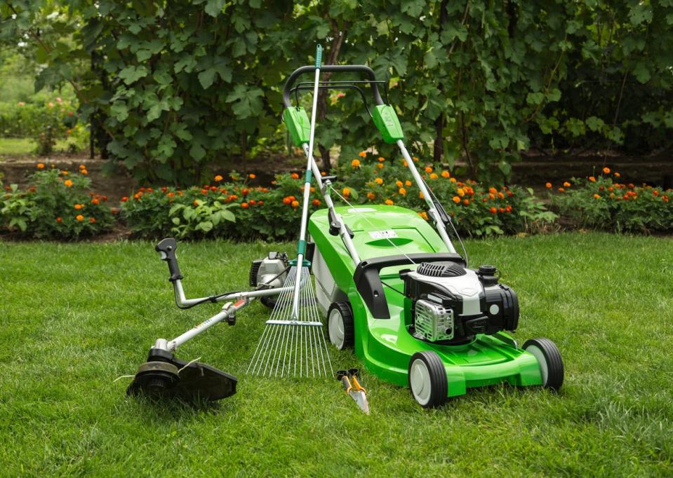 A photos of a green lawn mower, a trimmers, and small hand tools, and a rake.