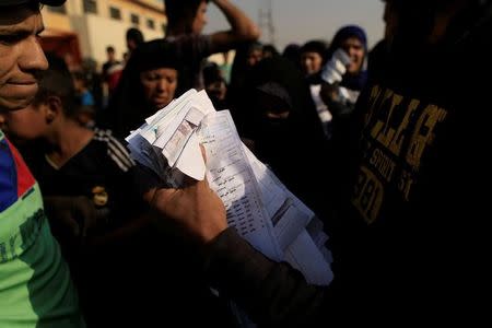 An aid worker collects vouchers for humanitarian aid from registered displaced people outside the processing center in Qayyara, south of Mosul, Iraq October 25, 2016. REUTERS/Zohra Bensemra