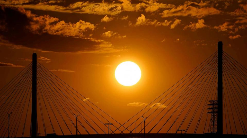 PHOTO: The sun sets over the Long Beach International Gateway ahead of Hurricane Hilary in Long Beach, Calif., Aug. 19, 2023. (Damian Dovarganes/AP)