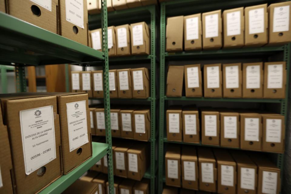 Brown boxes with white labels and stacked on green shelving racks.