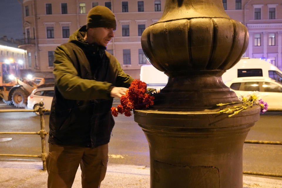 A man lays flowers near the site of an explosion at a cafe in St. Petersburg, Russia, Sunday, April 2, 2023. An explosion tore through a cafe in the Russian city of St. Petersburg on Sunday, and preliminary reports suggested a prominent military blogger was killed and more than a dozen people were injured. (AP Photo)