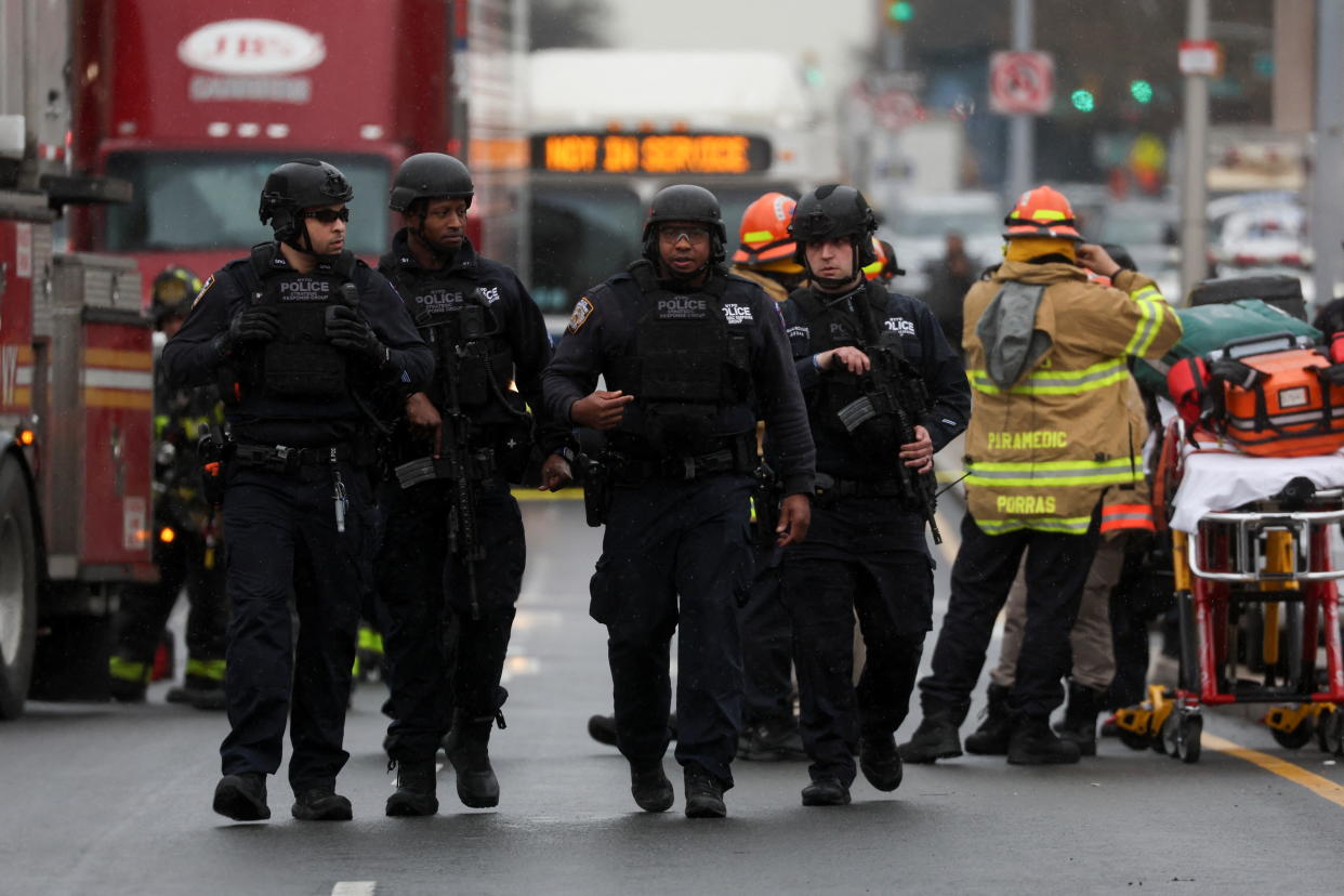 Police officers wearing helmets walk along a Brooklyn street.