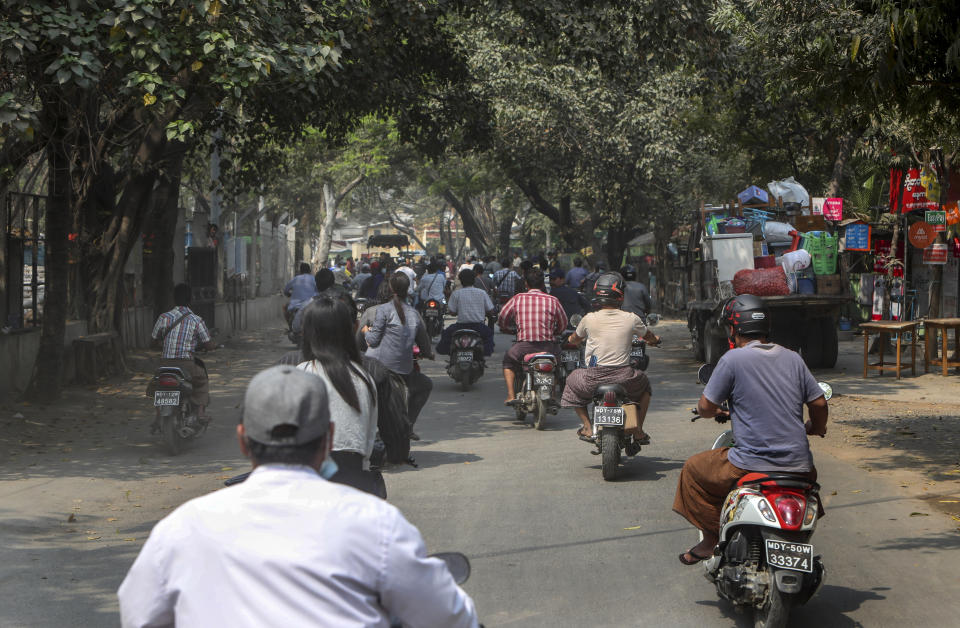 People ride motorbikes as a convoy of soldiers and policemen arrive with bulldozers to remove makeshift barricades made by anti-coup protesters in Mandalay, Myanmar, Tuesday, March 9, 2021. Demonstrators in Myanmar's biggest city came out Monday night for their first mass protests in defiance of an 8 p.m. curfew, seeking to show support for an estimated 200 students trapped by security forces in a small area of one neighborhood. (AP Photo)