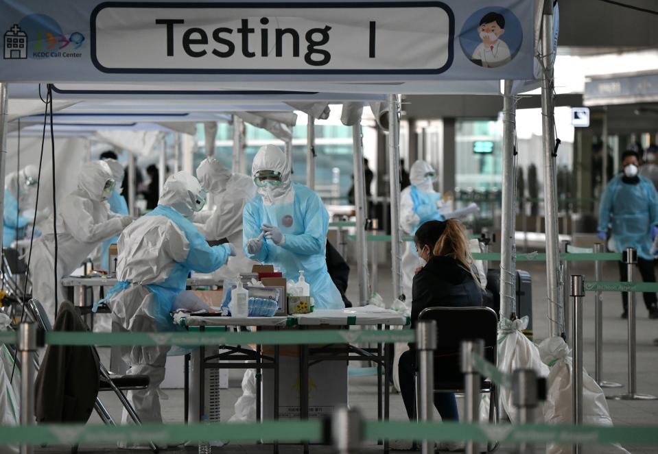 TOPSHOT - Medical staff wearing protective clothing take test samples for the COVID-19 coronavirus from a foreign passenger at a virus testing booth outside Incheon international airport, west of Seoul, on April 1, 2020. - The first charter flight arranged by South Korean government to evacuate its citizens from coronavirus-hit Italy returned home with 309 citizens on April 1, amid the worsening virus outbreak in the European country. (Photo by Jung Yeon-je / AFP) (Photo by JUNG YEON-JE/AFP via Getty Images)