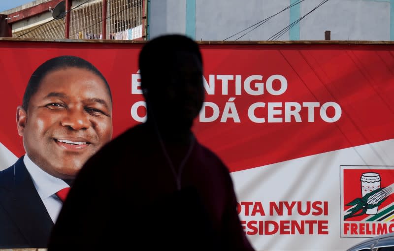 FILE PHOTO: A local walks past a billboard with a picture of Mozambique's president and leader of the Frelimo Party, Filipe Nyusi, ahead of Tuesday's provincial and legislative elections