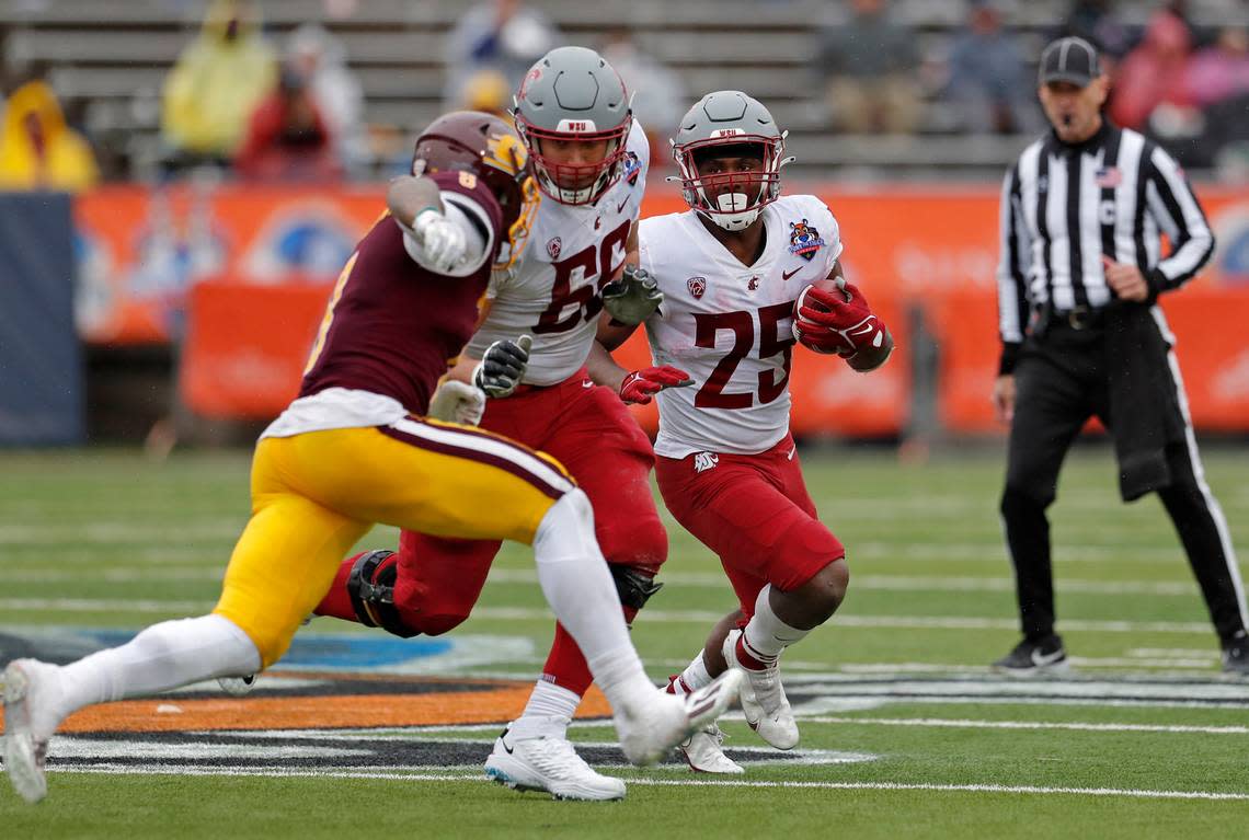 Washington State running back Nakia Watson (25) carries the ball as his offensive lineman Ma’ake Fifita (66) blocks Central Michigan linebacker Troy Brown (8) during the second half of the Sun Bowl NCAA college football game in El Paso, Texas, Friday, Dec. 31, 2021. Central Michigan won 24-21. (AP Photo/Andres Leighton)