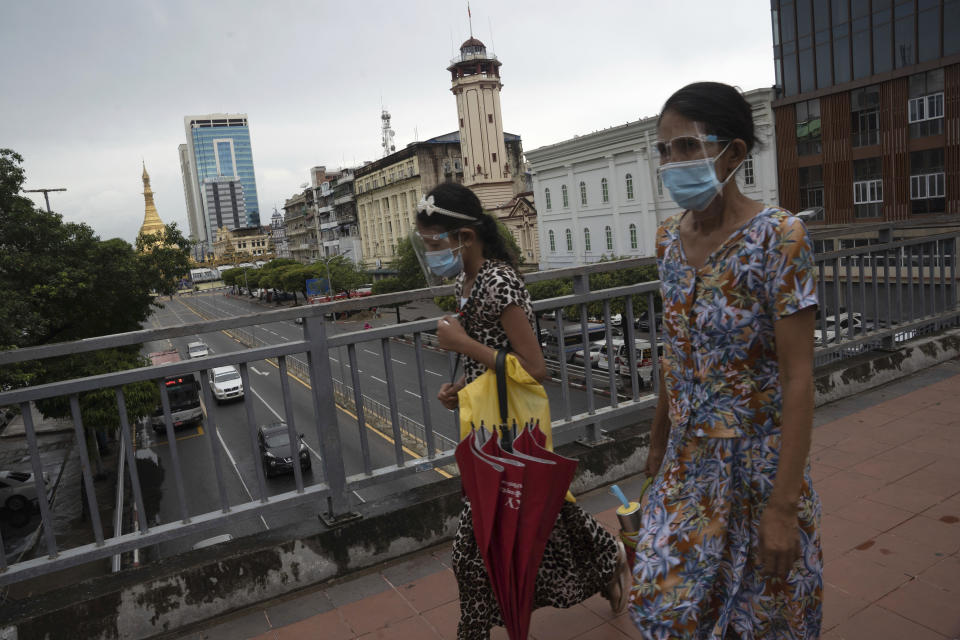 Pedestrians wearing face shields and masks walk at an overhead crossing at Sule Pagoda Road in Yangon, Myanmar,Monday, Sept. 21, 2020. Myanmar, faced with a rapidly rising number of coronavirus cases and deaths, has imposed the tightest restrictions so far to fight the spread of the disease in Yangon, the country's biggest city and main transportation hub. (AP Photo/Pyae Sone Win)