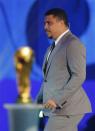 Former Brazill soccer player Ronaldo walks past by the World Cup trophy on stage during the draw for the 2014 World Cup at the Costa do Sauipe resort in Sao Joao da Mata, Bahia state, December 6, 2013. REUTERS/Paulo Whitaker