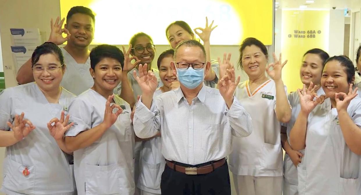 Mr Wang (centre with face mask), who was Singapore's first confirmed COVID-19 patient, poses with medical staff at Singapore General Hospital upon being discharged. (PHOTO: Screenshot/Lianhe Zaobao)