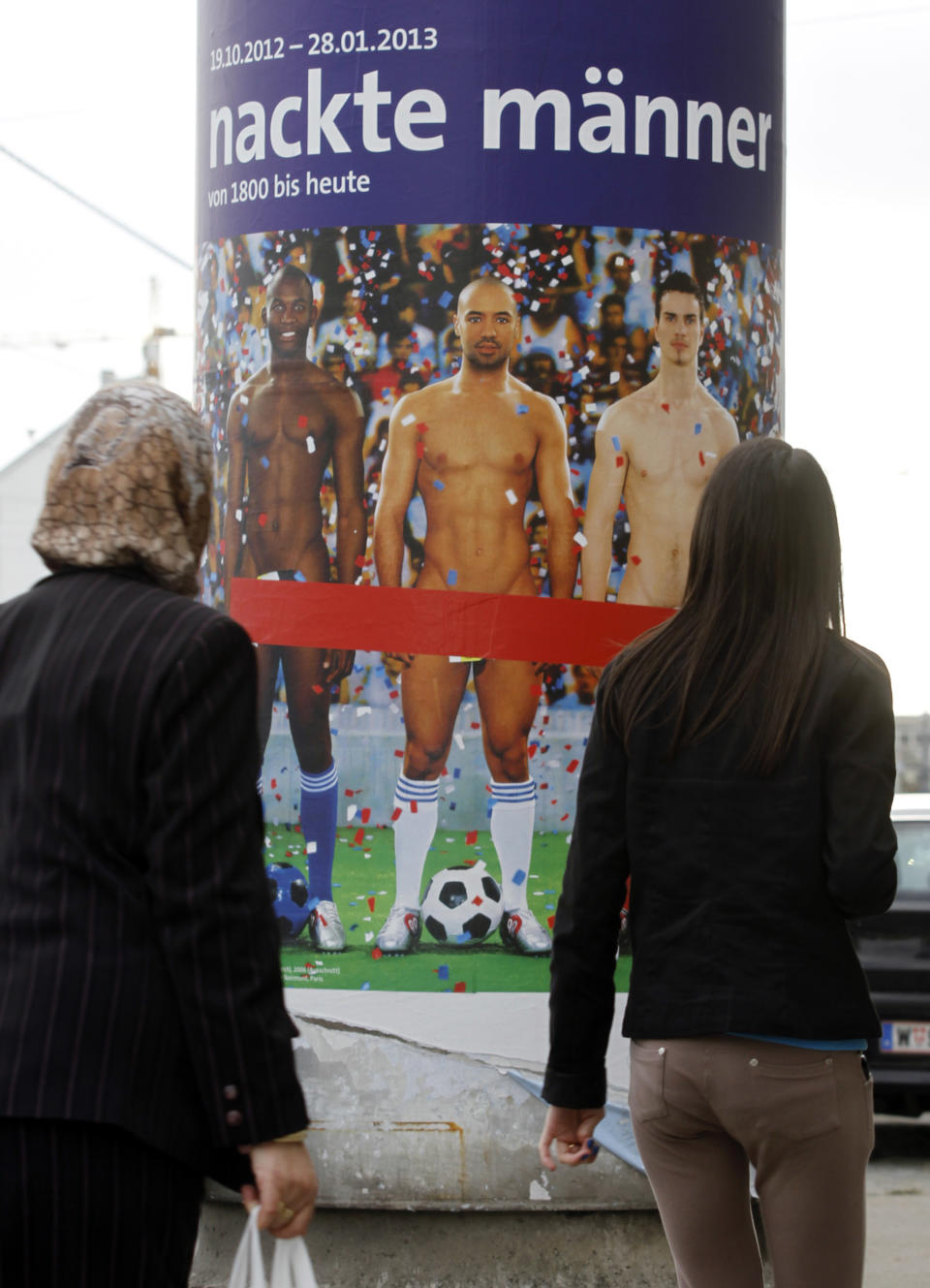 In this picture taken Oct. 18, 2012 two people walk past a poster showing three naked men which has had red tape added to cover the sensitive parts of the three men, in Vienna, Austria. Poster reads: "Naked Men". A prestigious Vienna museum, The Leopold Museum, has been forced to cover up a graphic poster advertising a new show devoted to male nudity, after protests that it is offensive. The show — "Nude Men from 1800 to Today" — opened its doors Friday Oct. 20, looking at how artists have dealt with the theme of male nudity over the centuries. (AP Photo/Ronald Zak)