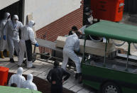 FILE - In this Monday, March 30, 2020, file photo, officials wearing protective face masks and suits as a preventive measure against the spread of the coronavirus carry the coffin of a victim, who died of COVID-19 onto a hearse truck, at a morgue in Istanbul. When Turkey changed the way it reports daily COVID-19 infections, it confirmed what medical groups and opposition parties have long suspected — that the country is faced with an alarming surge of cases that is fast exhausting the Turkish health system. The official daily COVID-19 deaths have also steadily risen to record numbers in a reversal of fortune for the country that had been praised for managing to keep fatalities low. With the new data, the country jumped from being one of the least-affected countries in Europe to one of the worst-hit.(AP Photo/Emrah Gurel, File)