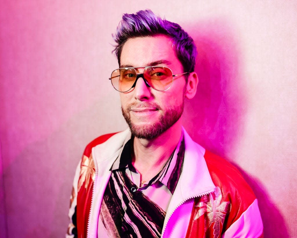 Singer and NSYNC member Lance Bass poses for a photo with pink hair and big sunglasses as a Super Bowl event