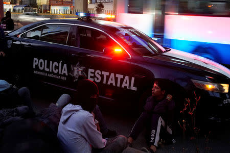 Migrant Nery Josvel, 20, (R), from Honduras, sits beside a police car as he waits for transportation during his journey towards the United States, in Mexico City, Mexico, January 31, 2019. REUTERS/Alexandre Meneghini