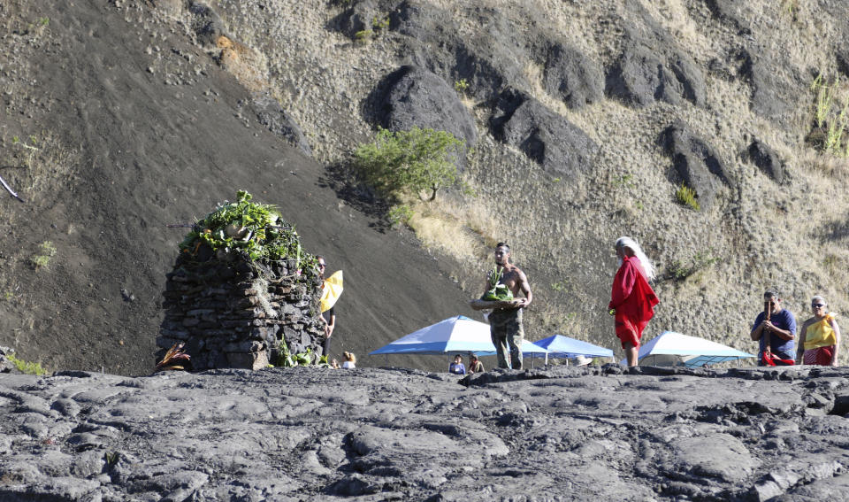 Native Hawaiian activists pray at the base of Hawaii's Mauna Kea on Sunday, July 14, 2019. Hundreds of demonstrators are gathered at the base of Hawaii's tallest mountain to protest the construction of a giant telescope on land that some Native Hawaiians consider sacred. State and local officials will try to close the road to the summit of Mauna Kea Monday morning to allow trucks carrying construction equipment to make their way to the top. Officials say anyone breaking the law will be prosecuted. Protestors have blocked the roadway during previous attempts to begin construction and have been arrested. (AP Photo/Caleb Jones)