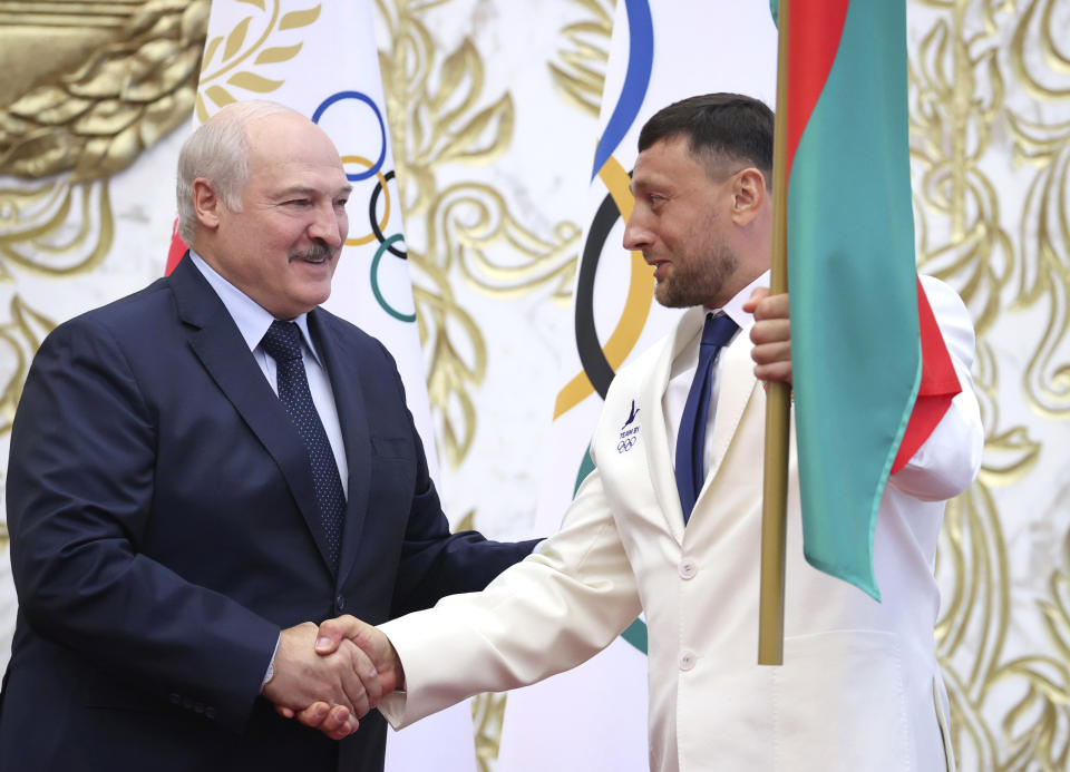 FILE In this file photo taken on Friday, July 9, 2021, Belarus President Alexander Lukashenko, left, presents the national flag to the captain of Belarus National Olympic team Ivan Tikhon ahead of the Summer Olympics Games in Tokyo, Minsk, Belarus. Lukashenko, who has a keen interest in sports and served as the head of the Belarus National Olympic Committee for nearly a quarter-century before handing over the post to his older son in February, has sternly warned the country's Olympic athletes that they better show high performance. (Maxim Guchek/BelTA Pool Photo via AP, File)