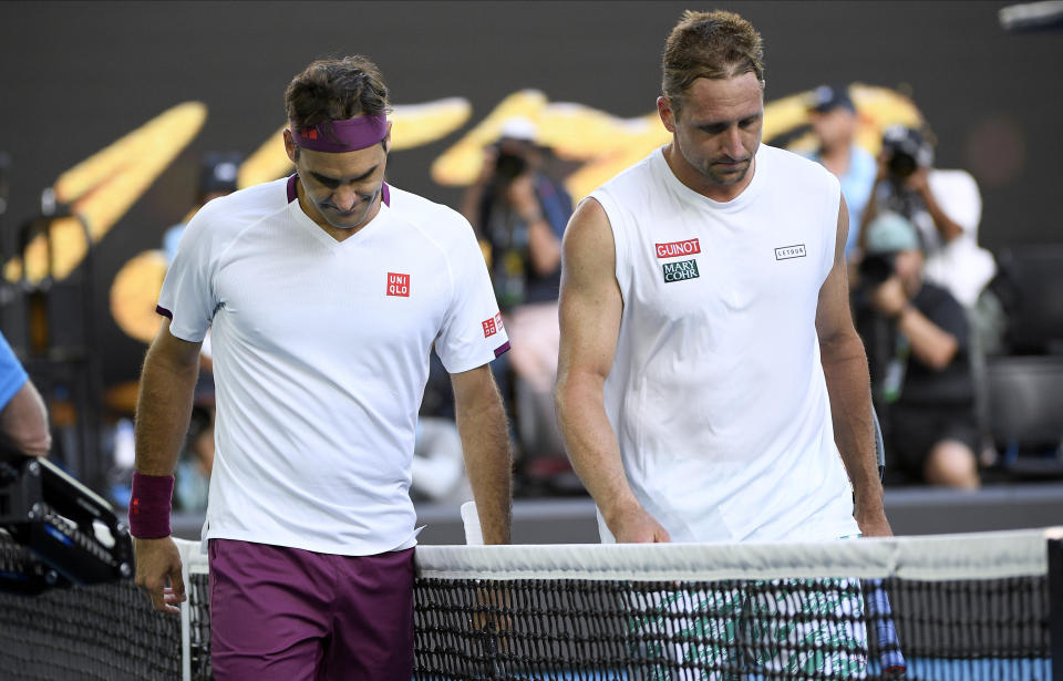 Switzerland's Roger Federer, left, walks with Tennys Sandgren of the U.S. after winning their quarterfinal match at the Australian Open tennis championship in Melbourne, Australia, Tuesday, Jan. 28, 2020. (AP Photo/Andy Brownbill)