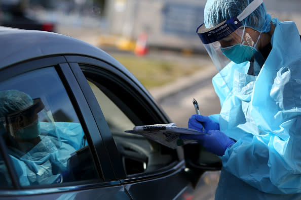 Registered Nurse Ali Murphy conducts a COVID-19 swab test as large crowds queue at a Bondi Beach drive-through testing clinic in Sydney.