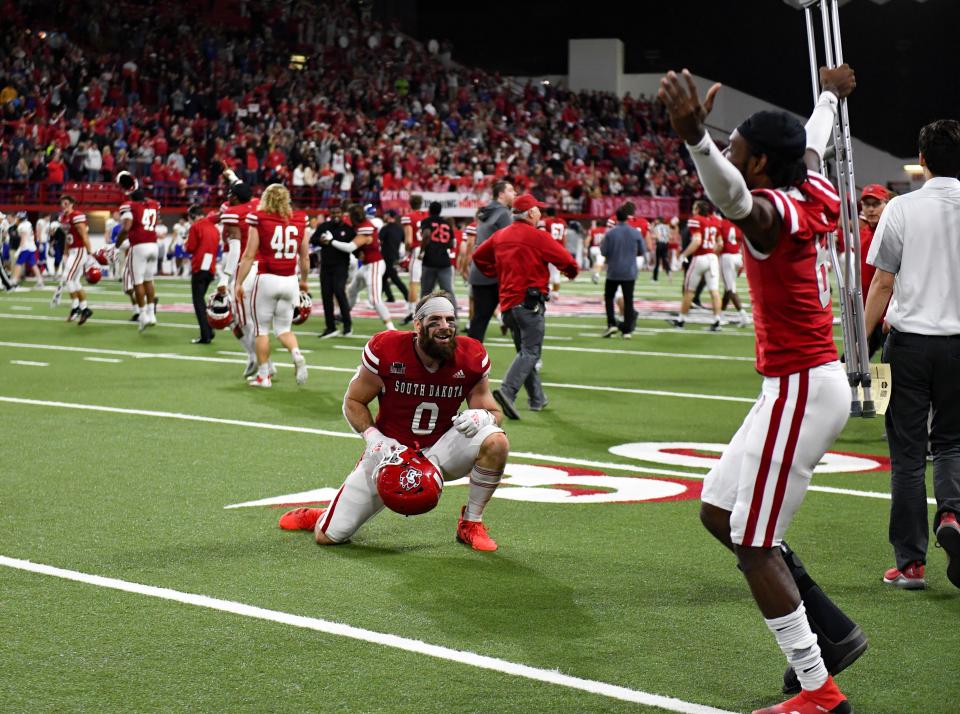 South Dakota's Brett Samson greets injured teammate Josiah Ganues on the field while celebrating the team's win with a Hail Mary pass in their game against South Dakota State on Saturday, November 13, 2021, at the DakotaDome in Vermillion.