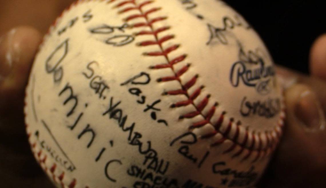 Mourners sign a baseball that will be given to the Doyle family by the Flores family.