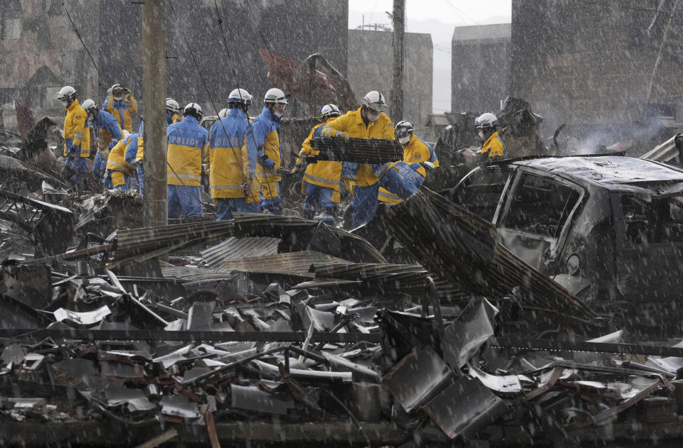 Police officers remove the debris from a fire at a market in Wajima, Ishikawa prefecture, Japan Saturday, Jan. 6, 2024. A series of powerful quakes set off a large fire in the town of Wajima, as well as tsunamis and landslides in the region. (Kyodo News via AP)