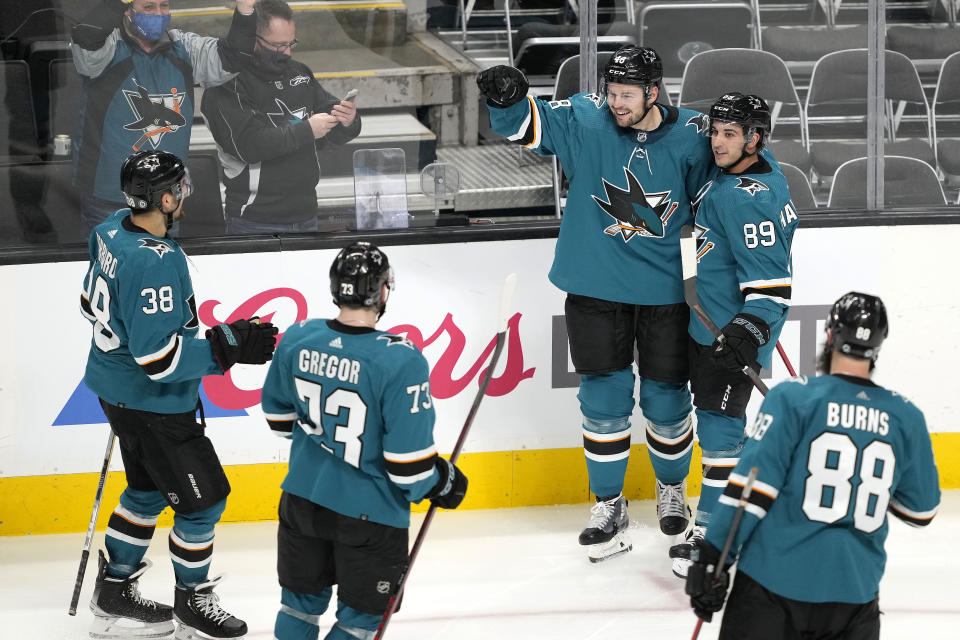 San Jose Sharks center Tomas Hertl celebrates with Jayden Halbgewachs (89), Mario Ferraro (38), Noah Gregor (73) and Brent Burns (88) after scoring a goal against the Arizona Coyotes during the third period of an NHL hockey game Tuesday, Dec. 28, 2021, in San Jose, Calif. San Jose won 8-7 in a shootout. (AP Photo/Tony Avelar)