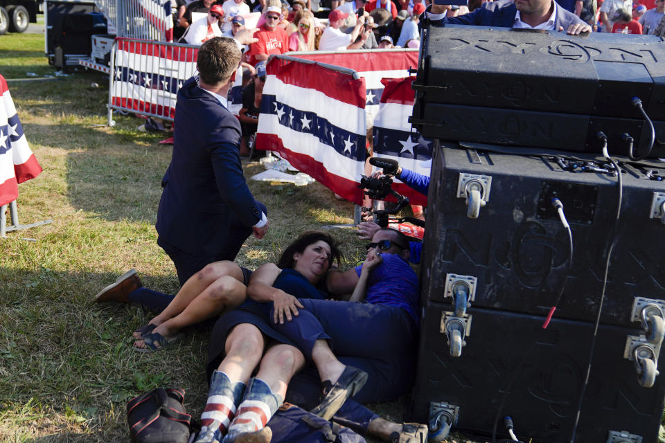 Civiles se cubren al tiempo que agentes del Servicio Secreto de Estados Unidos rodean al expresidente Donald Trump durante un acto de campaña, el sábado 13 de julio de 2024, en Butler, Pensilvania. (AP Foto/Evan Vucci)